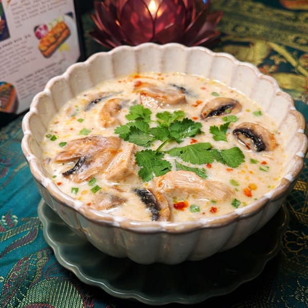 Creamy Tom Kha Gai soup with chicken, mushrooms, and cilantro in a decorative bowl.